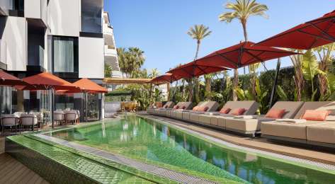 Hotel pool with sunbeds around the edge.