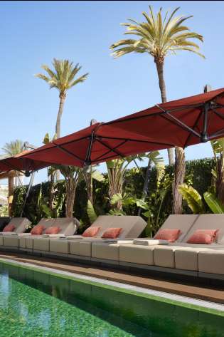 Hotel pool with sunbeds around the edge.