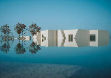 Pool at white hotel with three trees .