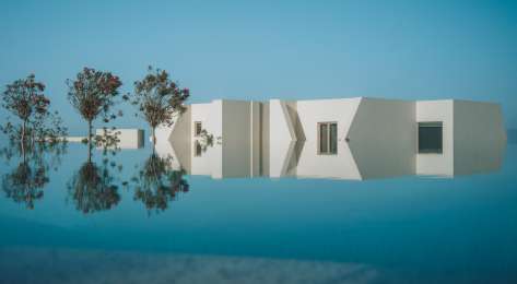 Pool at white hotel with three trees .