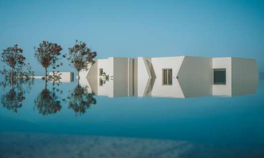 Pool at white hotel with three trees .