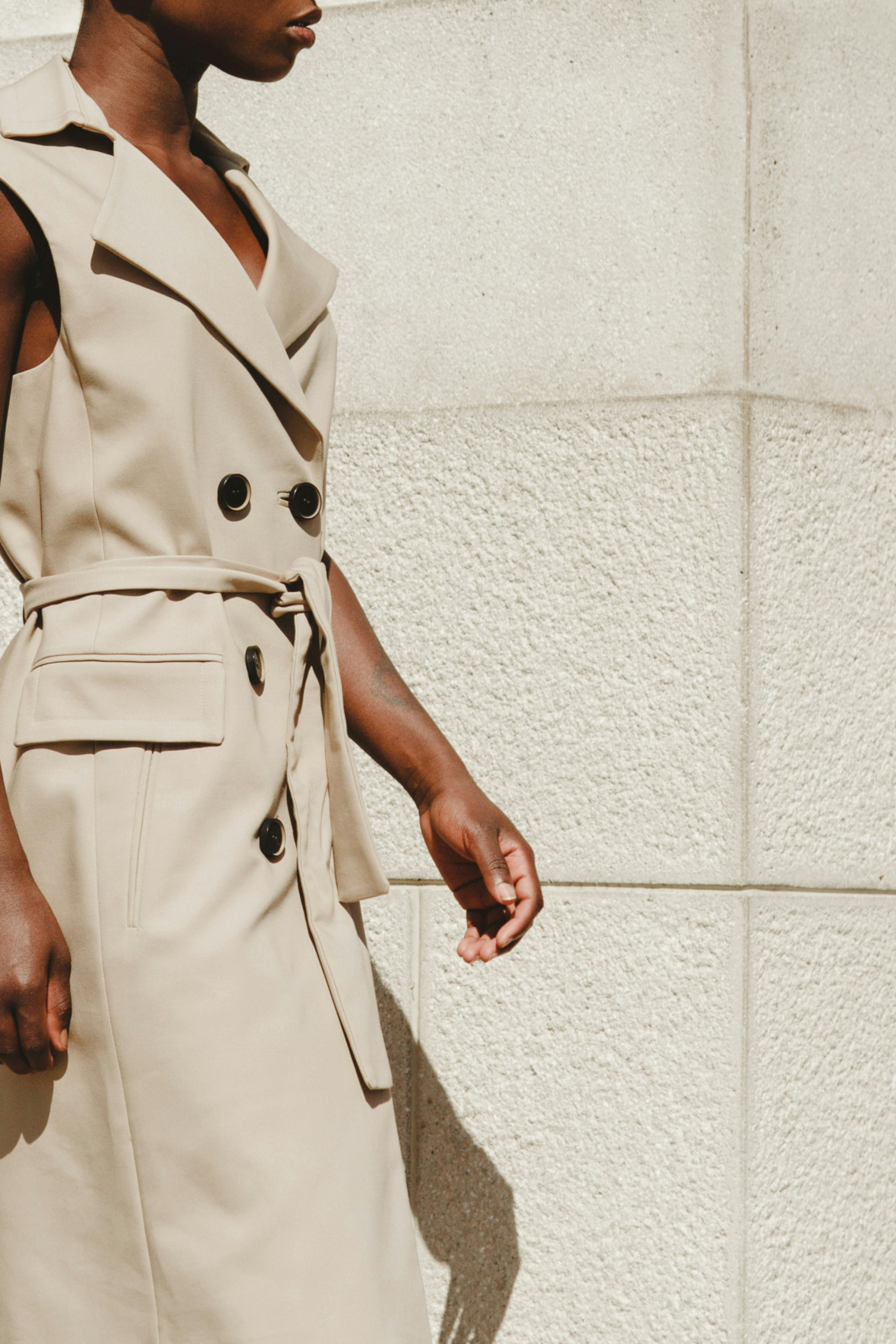 model wearing sleeveless trench coat in beige
