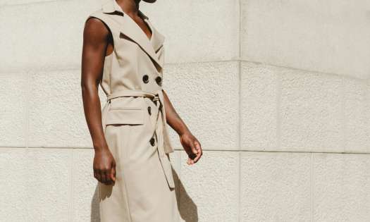Model wearing sleeveless trench coat in beige.