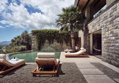 View of small pool at hotel surrounded by sun loungers.