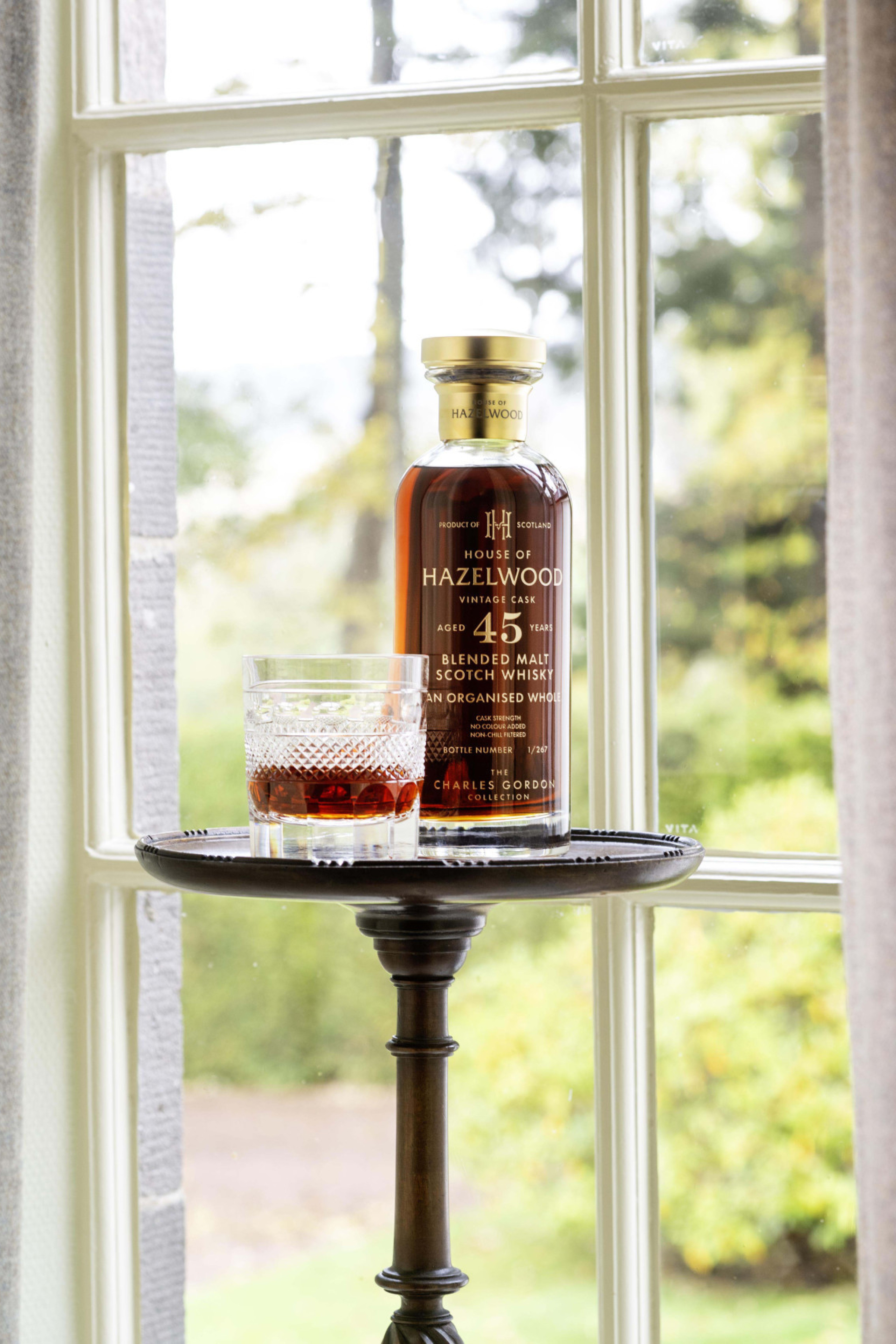 bottle of whisky and whisky glass styled next to window 