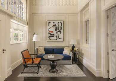 Hotel parlour room with sofa and leather chair .