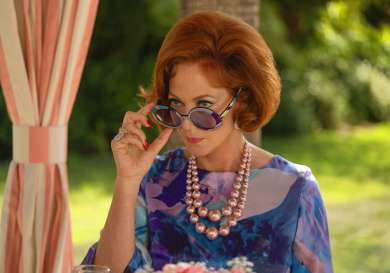 Actress on set of palm royale tv series in blue floral dress.