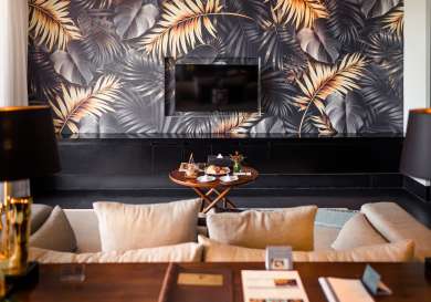 Hotel suite with botanical wallpaper and dark hues.