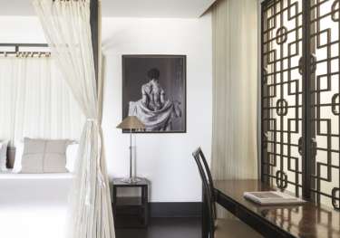 Hotel bedroom in thailand with four-posted bed and wooden desk.