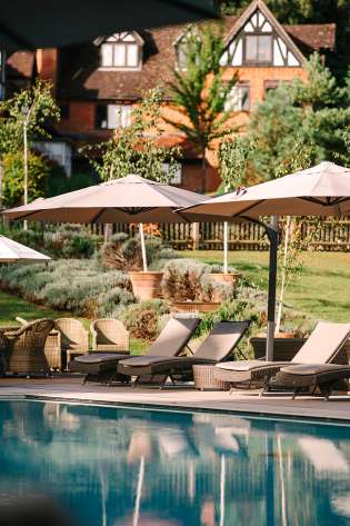 Hotel pool with umbrellas and deckchairs.