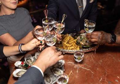 Group of people clinking martini glasses inside restaurant.