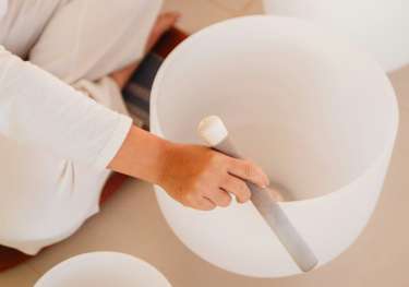 Person using set of white singing bowls .