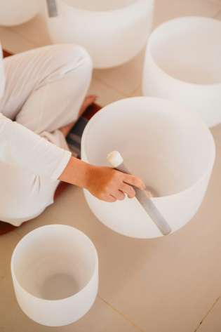 Person using set of white singing bowls .