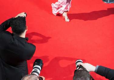 Person walking red carpet with photographers .