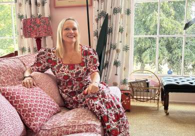 Molly russell posing on sofa in red print puff sleeve dress.