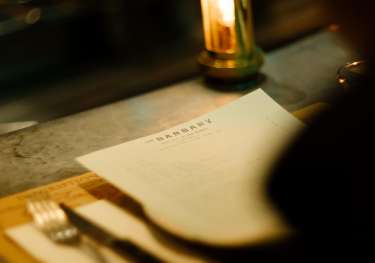 Photo of someone looking at menu at barbary restaurant .