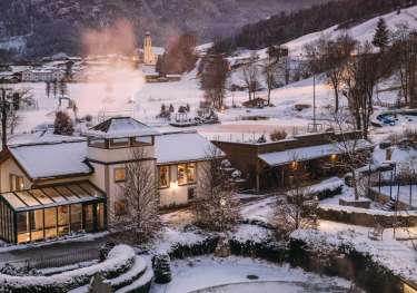 Aerial view of hotel pool with snowy hills in the background .