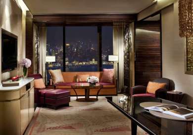 Hotel living room area with seating, table and mounted TV.
