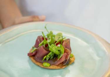 Person holding small dish on chunky blue glazed plate.