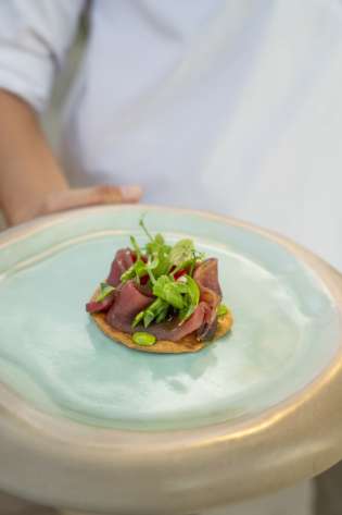 Person holding small dish on chunky blue glazed plate.