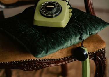 Retro green phone styled on a velvet chair.