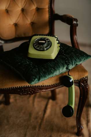 Retro green phone styled on a velvet chair.