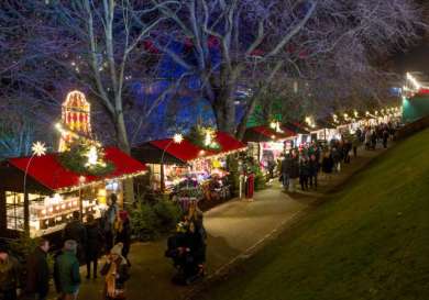 Stalls with red canopies display festive goods, illuminated by twinkling lights.