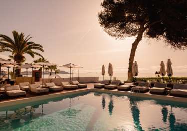Hotel riomar ibiza swimming pool with lounge beds and parasols .