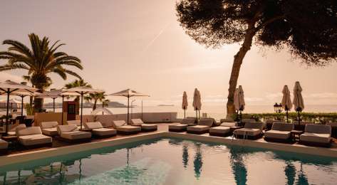 Hotel riomar ibiza swimming pool with lounge beds and parasols .