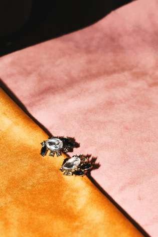 Gem earrings on pink and orange materials.