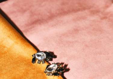 Gem earrings on pink and orange materials.