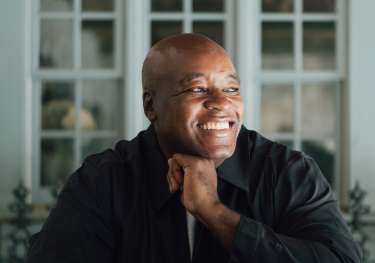 Headshot of ronald ndoro mind sat at table.