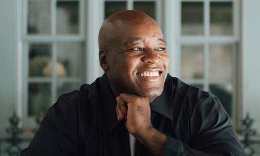 Headshot of ronald ndoro mind sat at table.