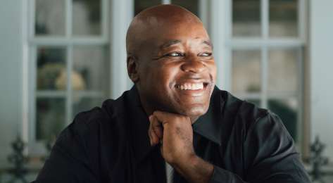 Headshot of ronald ndoro mind sat at table.