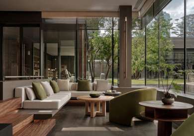 Hotel lobby area with floor-to-ceiling glass windows and trees outside .