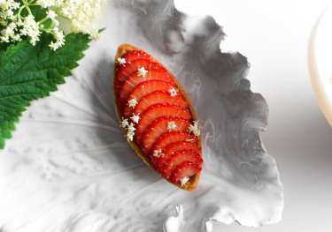 Strawberry dessert on leaf-shaped plate.