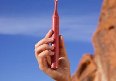Person holding suri toothbrush outside.