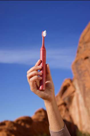 Person holding suri toothbrush outside.
