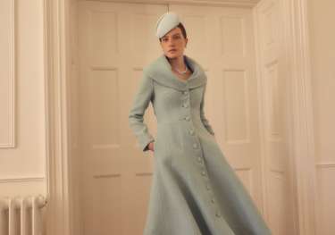 Model posing in duck egg blue dress and matching hat .