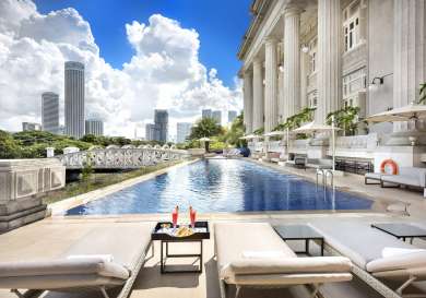 Pool beside a grand building with cityscape backdrop.