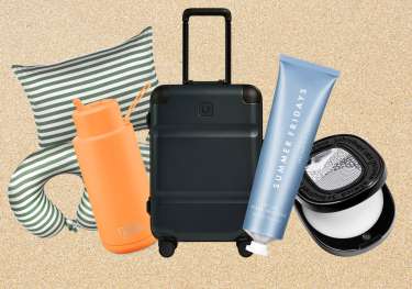 Travel-themed gift items arranged on white sand background.