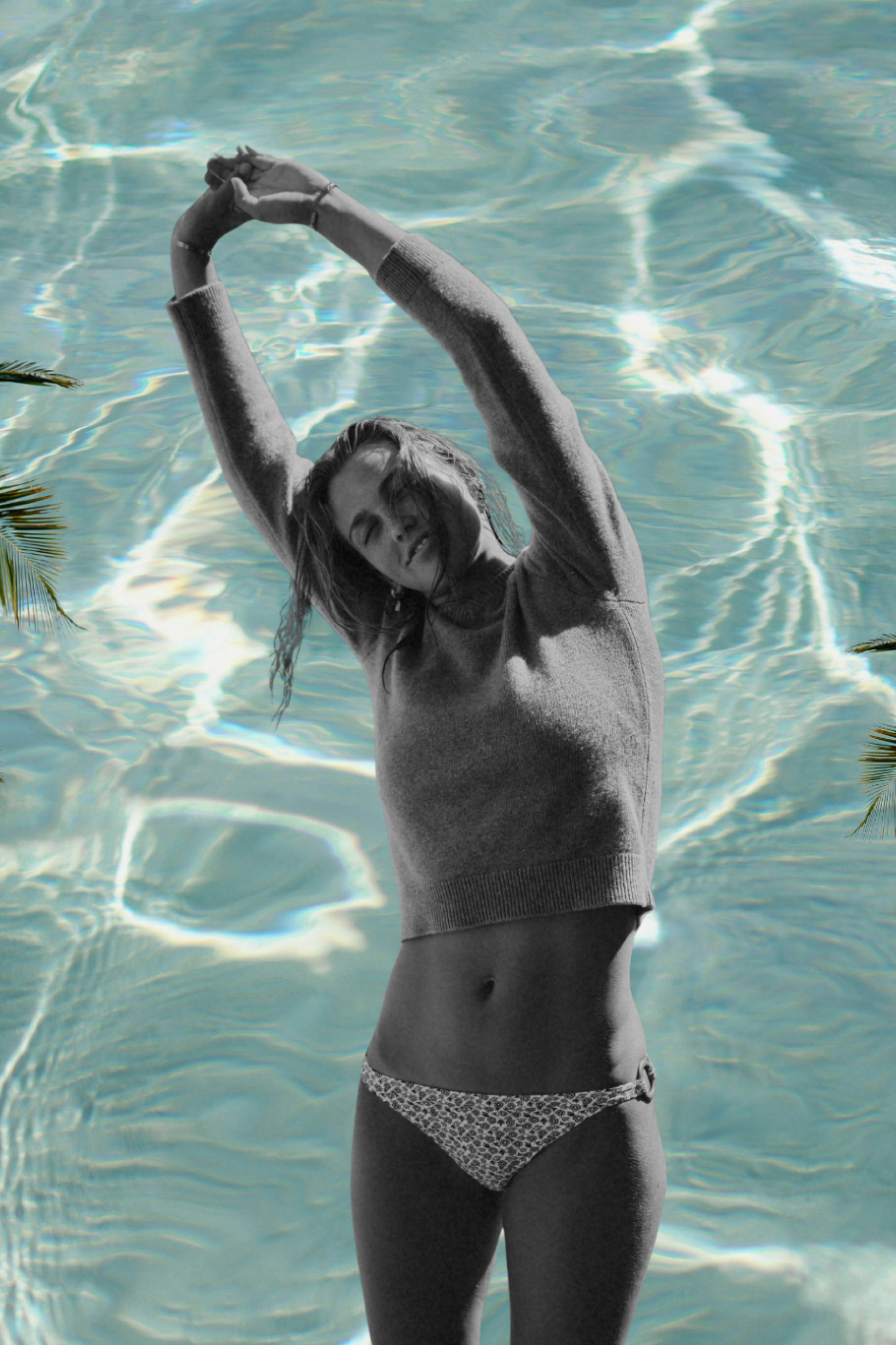 model posing in bikini with palm trees and pool background