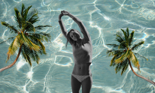 Model posing in bikini with palm trees and pool background.