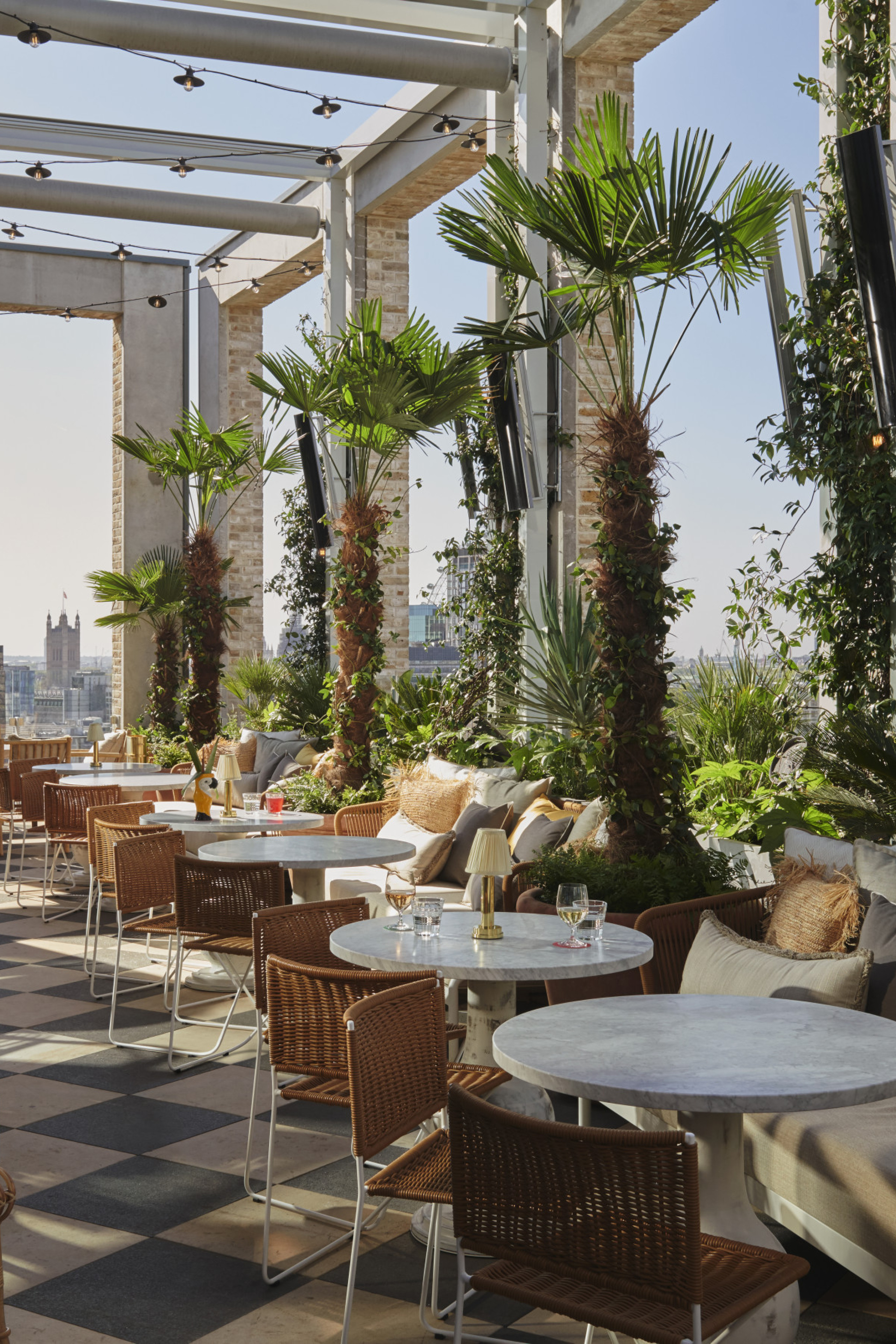 rooftop bar with round tables, chairs, and plants 