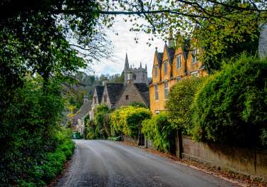 Road in the cotswolds with yellow house .