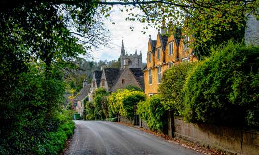 Road in the cotswolds with yellow house .