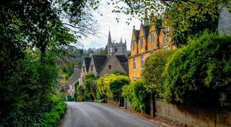 Road in the cotswolds with yellow house .