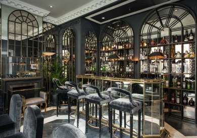 The franklin hotel bar area with dark grey velvet stools and a mirrored bar.