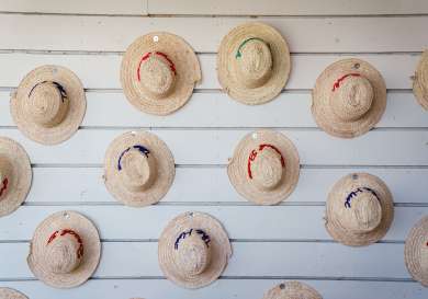 Straw hats dotted along panelled wall .
