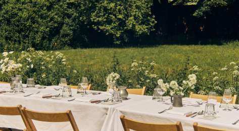 Outdoor tables with linen tablecloths and jars of flowers.